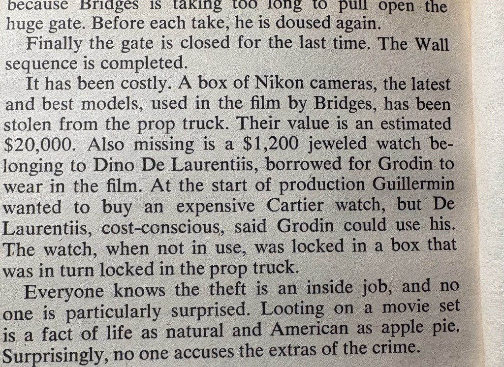 A close-up photograph of a printed text page discussing the theft of valuable items, including a box of Nikon cameras worth $20,000 and a $1,200 jeweled watch belonging to Dino De Laurentiis, from a prop truck on a movie set.