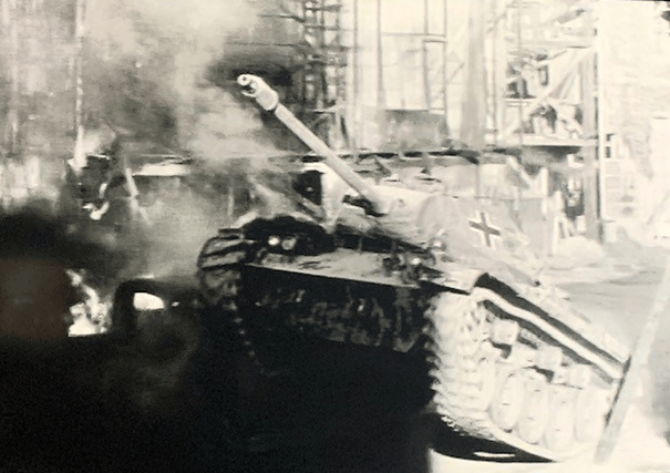 A black and white image of a tank with a German cross insignia amidst smoke and debris, suggesting a war-torn environment.