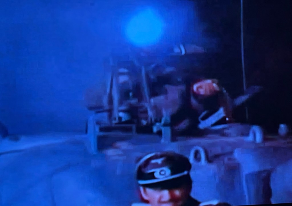 A scene featuring a military vehicle with soldiers on board, illuminated by a blue light, set against a dark backdrop.