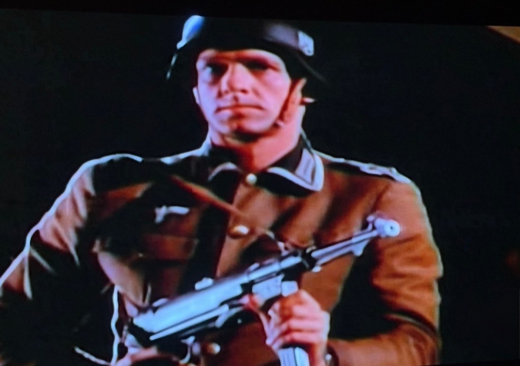 A soldier in a military uniform holding a weapon, standing in a dark environment.