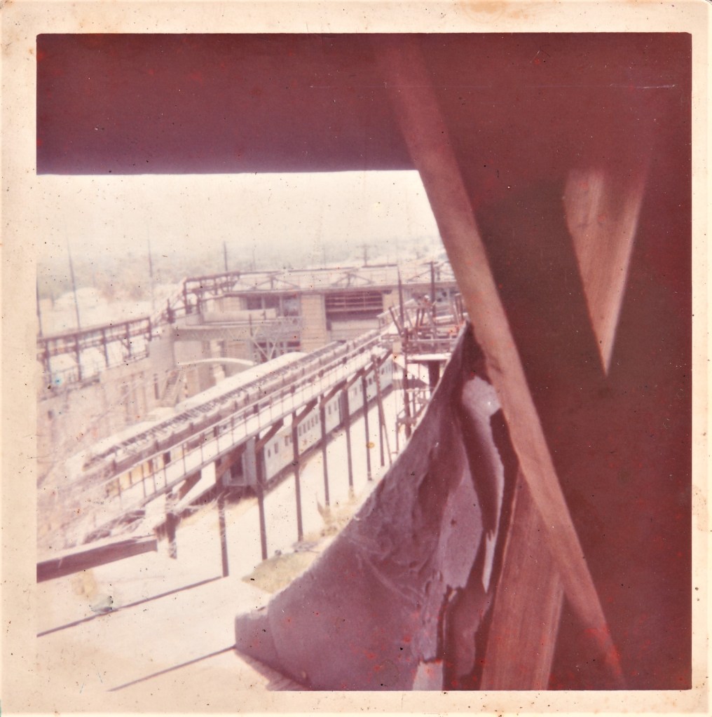 View of industrial construction site with partially built structures and scaffolding, taken from a high vantage point.