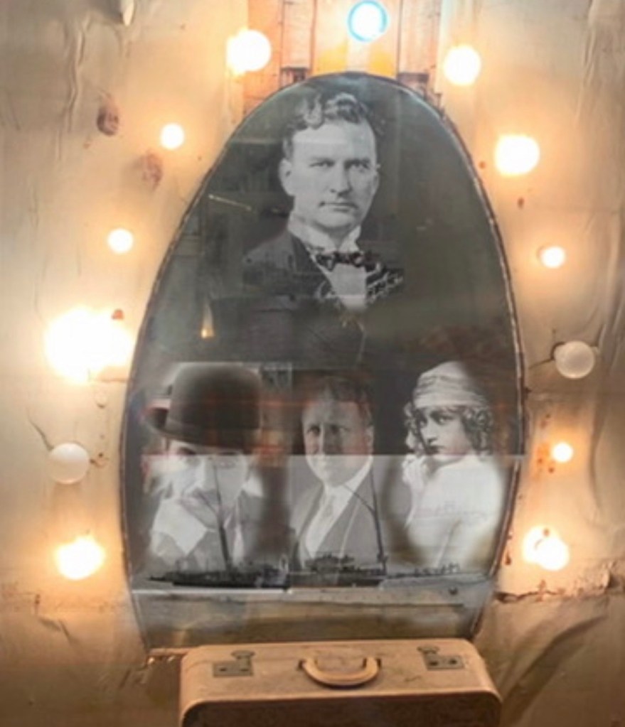 A vintage mirror surrounded by light bulbs, featuring black and white portraits of several people in early 20th-century attire.