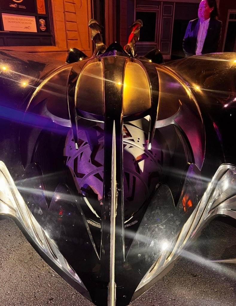 Close-up view of a sleek, custom-designed black vehicle with metallic accents, showcasing intricate details and a reflective surface.