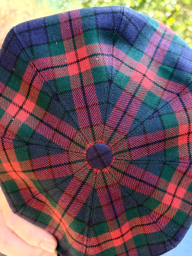 The inside view of a traditional Scottish flat cap featuring a red and green tartan pattern.
