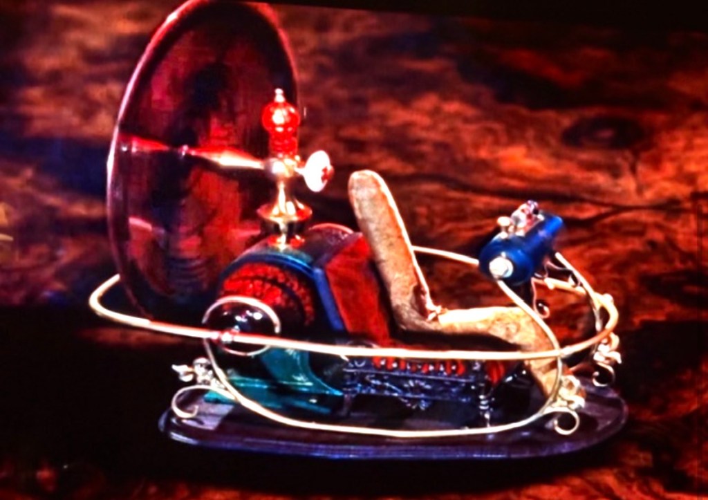 A vintage-looking time machine model featuring a colorful design with a seat, spinning disk, and various mechanical components.